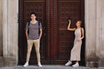 Jeune couple joyeux et ludique en vêtements décontractés posant devant la belle vieille porte — Photo de stock