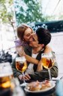 Весела молода приваблива жінка цілує чоловіка, насолоджуючись освіжаючим напоєм — стокове фото