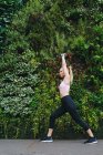 Junge blonde Frau macht Dehnübungen nach einer Laufeinheit mit grünem Kräuterhintergrund — Stockfoto