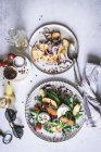 Platos de arriba con ensaladas gourmet hechas de duraznos, cebolla roja, queso, aceite y pimienta negra sobre la mesa - foto de stock