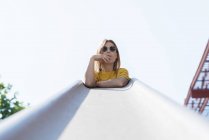 Jeune femme blonde fumant la cigarette et regardant la caméra sur fond blanc penché dans les escaliers main courante — Photo de stock