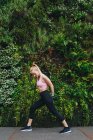 Молода блондинка робить подовження вправи після бігового сеансу з зеленим трав'яним фоном — стокове фото