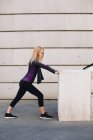 Junge blonde Frau dehnt sich nach einer Laufeinheit im Treppenhaus — Stockfoto