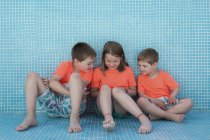 Crianças sentadas em piscina vazia e livro de leitura — Fotografia de Stock