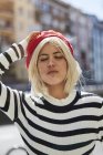 Young blonde woman in striped black and white shirt and red French cap on blurred background — Stock Photo