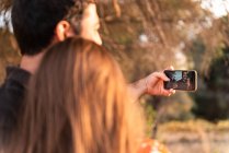 Happy young couple kissing and taking selfie in summer nature — Stock Photo