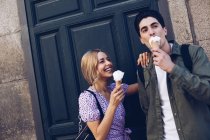 Веселая молодая привлекательная женщина и ее парень едят мороженое на открытом воздухе — стоковое фото