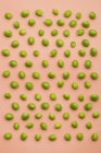 Set of peas scattered on salmon background — Stock Photo