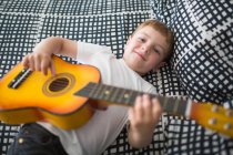 Kleiner blonder Junge spielt Spielzeuggitarre — Stockfoto