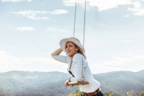Happy girl with hat next to a swing at sunset — Stock Photo