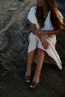 Jeune mannequin femme assise sur le rocher et regardant loin — Photo de stock