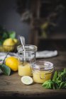Glass and jar of homemade lemon curd on wooden surface — Stock Photo