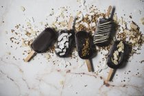 Sorvete de chocolate sortido picolés cobertos com coberturas na superfície de mármore — Fotografia de Stock