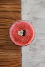 Bubble frothy tasty fragrant pink smoothie decorated with flower in glass on wooden and grey surface — Stock Photo