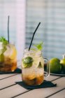 Mojito-Cocktail mit Limette, Minze, Rum, Soda und Eis im Einmachglas auf dem Tisch im Freien — Stockfoto