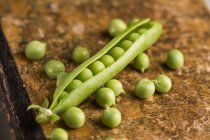 Peeled fresh peas and pea pod on grunge background — Stock Photo