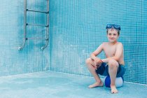 Мальчик сидит на мяче в пустом бассейне — стоковое фото