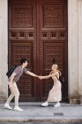 Joven pareja alegre y juguetona en ropa casual divirtiéndose durante citas al aire libre frente a la hermosa puerta vieja - foto de stock