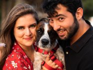 Smiling couple holding cute little dog in countryside — Stock Photo