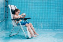 Ragazzo con smartphone seduto sul fondo della piscina vuota — Foto stock
