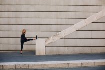 Молодая блондинка, растянувшаяся на лестнице после бега — стоковое фото