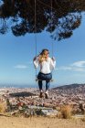 Blondes Mädchen schwingt mit Blick auf die Stadt im Hintergrund — Stockfoto