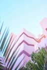 Rosafarbenes Gebäude mit komplexer geometrischer Form unter blauem Himmel — Stockfoto