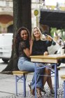 Schöne junge Frauen sitzen in Berliner Straßencafé und machen Selfie — Stockfoto