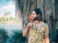 Nachdenklicher bärtiger Hipster-Mann reist mit Ukulele durch den Dschungel — Stockfoto