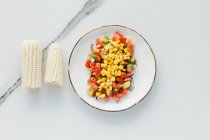 Served bowl with corn, cut tomatoes and zucchini on table — Stock Photo