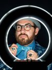 Handsome bearded man in glasses and looking away on black background and circle light — Stock Photo