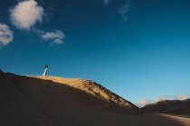 Frau in weißem Kleid steht in der Ferne auf sonnenerleuchteten sandigen Hügel in Tarifa, Spanien — Stockfoto