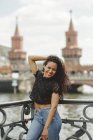 Beautiful hispanic model leaning on railing on summer day in Berlin on blurred background looking at camera — Stock Photo