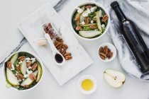 Servierte Schalen mit geschnittenen Birnen und Pekannüssen auf dem Tisch mit einer Flasche Sojasauce — Stockfoto