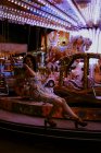 Schöne Frau genießt Fahrt auf Karussell auf Jahrmarkt während Sommerabend auf verschwommenem Hintergrund — Stockfoto