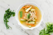 Served bowl of chicken soup with carrot, coriander and zucchini on table — Stock Photo