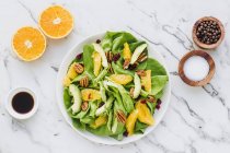 Served bowl with cut avocado, oranges, pecans and cranberries — Stock Photo