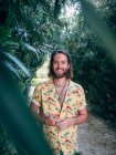 Pensif beau barbu hipster homme marche dans la jungle en regardant dans la caméra — Photo de stock