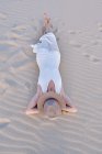 De arriba mujer en vestido blanco y sombrero acostado en la playa de arena en Tarifa, Cádiz - foto de stock