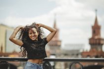 Летним днем в Берлине девушка на размытом фоне опирается на перила, глядя в камеру — стоковое фото