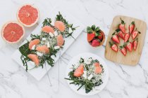 Schüsseln mit Erdbeeren, Grapefruit und Rucola auf dem Tisch, serviert auf Brettern — Stockfoto