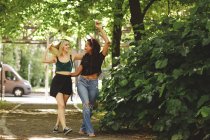 Cheerful women walking on green summer street in Berlin on sunny day — Stock Photo