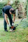 Caucasian man switching on and trimming an arizonica hedge with mechanical tools — Stock Photo