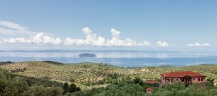 Vista panoramica sul mare verde con villa rossa e piantagione verde sulla riva contro il mare cristallino alla luce del sole, Grecia — Foto stock