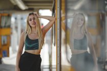 Junge fröhliche schöne blonde Frau steht auf gelbem Zug in Führerkabine in Berlin und blickt in die Kamera — Stockfoto