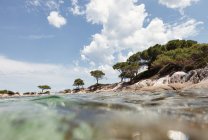 Pintoresca vista de la isla rocosa y el fondo del mar en el soleado día de verano en Halkidiki, Grecia - foto de stock