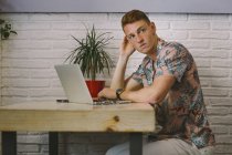 Uomo concentrato seduto con computer portatile a tavola in caffetteria — Foto stock