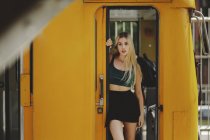 Young cheerful beautiful blonde woman standing on yellow train in drivers cabin in Berlin looking at camera — Stock Photo
