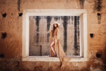 Elegante donna in abito lungo sulla finestra — Foto stock
