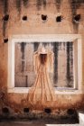 Elegant woman in long dress on window — Stock Photo
